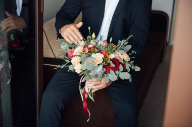 damat gelin için bekler ve elinde güzel bir düğün buketi tutar