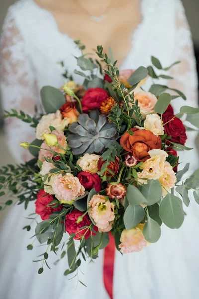 Novia en un vestido blanco sosteniendo un ramo de flores y vegetación — Foto de Stock