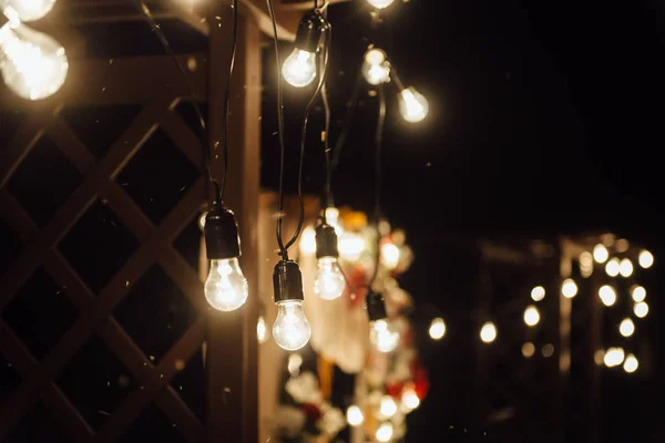 Ceremonia de boda nocturna. Una guirnalda de bombillas. velas en frascos de vidrio por la noche . — Foto de Stock