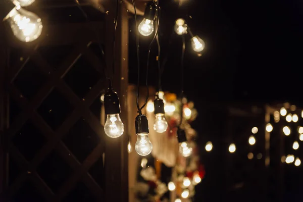 Cerimónia de casamento nocturno. Uma grinalda de lâmpadas. velas em frascos de vidro à noite . — Fotografia de Stock
