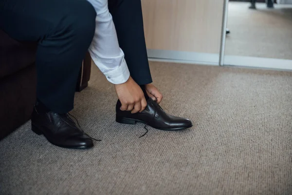 Бізнесмен зав'язує шнурки взуття на підлозі. Крупним планом — стокове фото