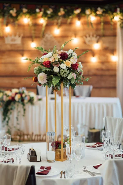 En komposition av blommor och grönt är på ett festligt bord på bröllopsfest salen. — Stockfoto