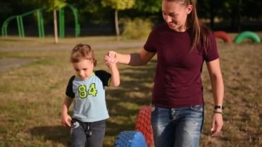 Annem oyun alanında oğluyla oynuyor. O renkli lastikler aracılığıyla elini açar.