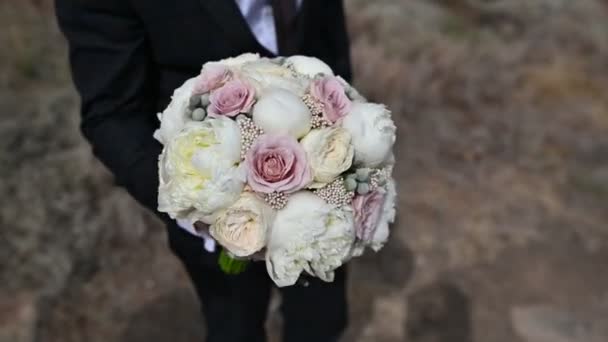 Der Bräutigam hält einen Hochzeitsstrauß in den Händen — Stockvideo
