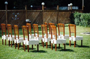 Dışarıdaki düğün töreninde konuklar için beyaz pelerinli sandalyeler.