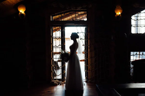 Чарівна наречена стоїть перед вікном. Дівчина стоїть біля вікна у своїй кімнаті. Силует — стокове фото
