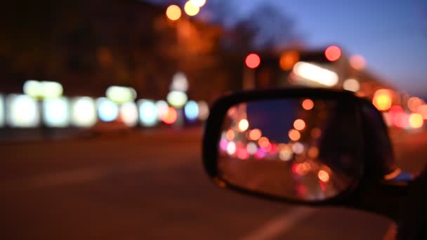 Nachts Autofahren. Blick aus dem Auto auf den Rückspiegel. verschwommene Stadtbeleuchtung. 4k — Stockvideo