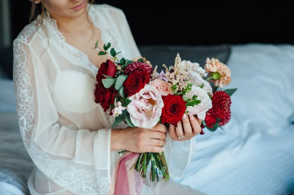 Una novia en un vestido blanco está sosteniendo un hermoso ramo de bodas — Foto de Stock