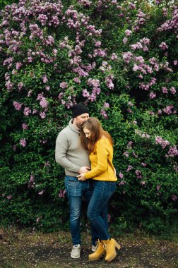Beautiful couple in love is hugging near a lilac bush. lifestyle photo
