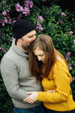 Beautiful couple in love is hugging near a lilac bush. lifestyle photo