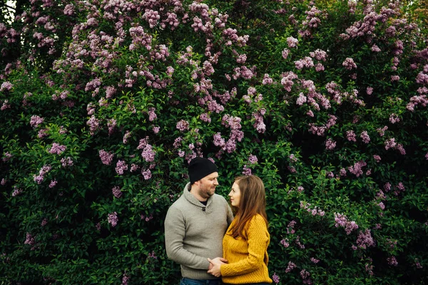 Belo casal apaixonado está abraçando perto de um arbusto lilás. estilo de vida foto — Fotografia de Stock