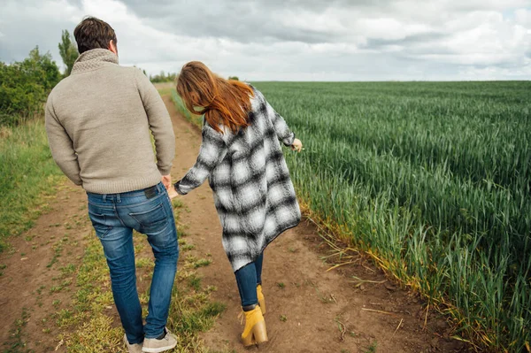 Les jeunes amoureux marchent près du champ de blé précoce. câlin et amusez-vous — Photo
