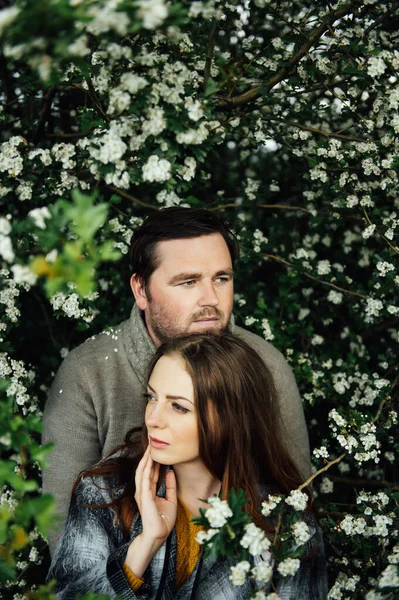 Beautiful couple in love is hugging near a white flowers bush. lifestyle photo