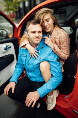 beautiful cheerful couple hugging in a red car