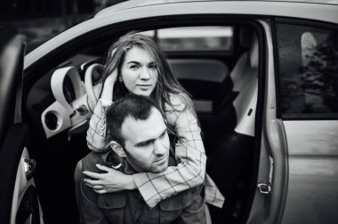 beautiful cheerful couple hugging in a red car