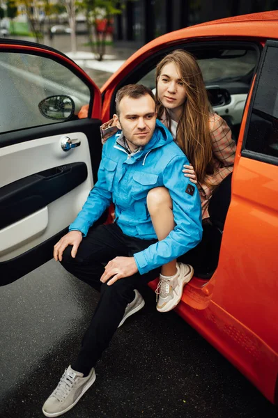 Beau couple joyeux câlin dans une voiture rouge — Photo