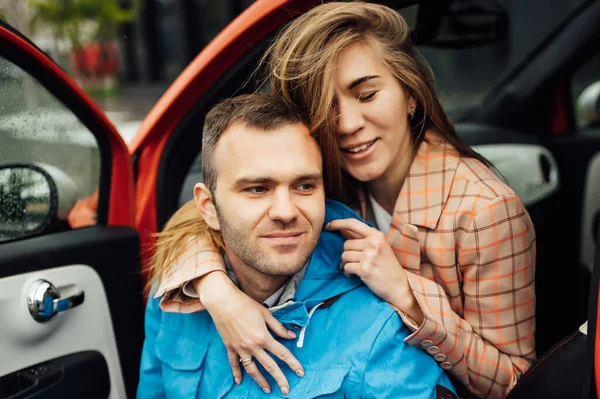 Beau couple joyeux câlin dans une voiture rouge — Photo