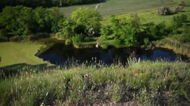 Gün batımında güneş ışığı alan güzel bir dağ manzarası. Rüzgar otları sallıyor, aşağısı göl.