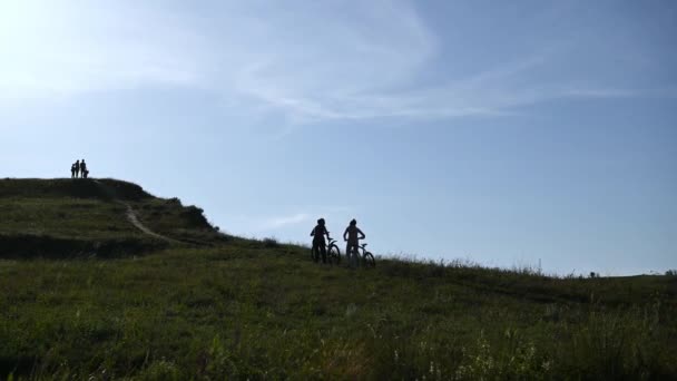 Δύο τουρίστες ανηφορίζουν με ποδήλατα, χαλαρώνουν και να εξετάσουμε την απόσταση. — Αρχείο Βίντεο