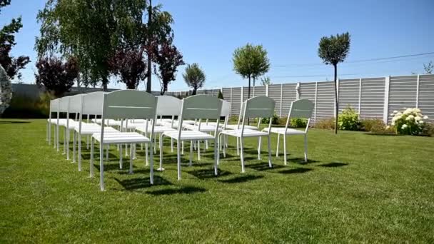 Variedade de cadeiras dobráveis brancas na área de recepção do casamento na cerimônia de casamento . — Vídeo de Stock