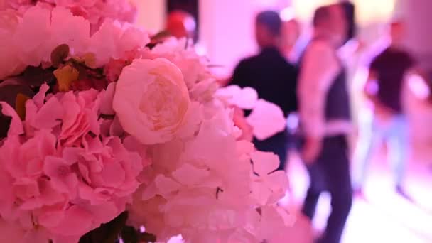 Folk dansar på blommornas bakgrund. BröllopsfestFolk dansar på bröllop — Stockvideo