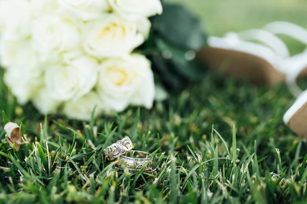 Beautiful white gold wedding rings lie on bridal shoes — Stock Photo, Image