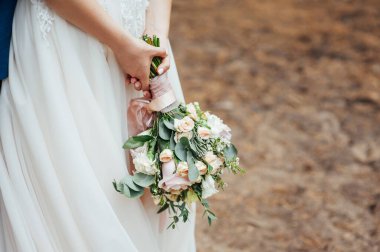 Gelin çok güzel bir düğün buketi tutuyor.