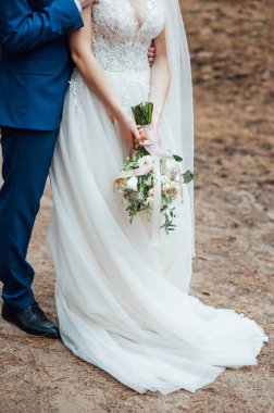 Mutlu gelin ve damat ellerinde buketle sarılıyorlar.