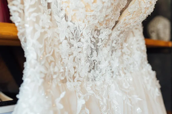 Une robe de mariée chic en soie accrochée à une bibliothèque. — Photo