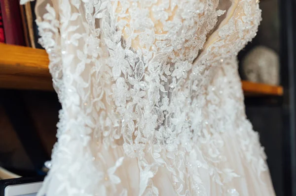 Um vestido de casamento de seda chique pendura em uma estante. — Fotografia de Stock