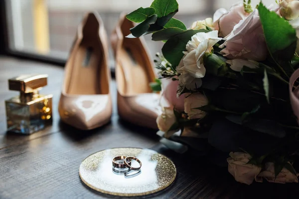 Luxusní svatební kytice vedle prstenů nevěsty a ženicha. Nevěsty boty s podpatky — Stock fotografie