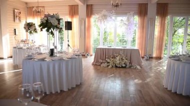 Sunucu, çiçekler, mumlar ve bardaklarla dolu bir masaya tabak koyar.