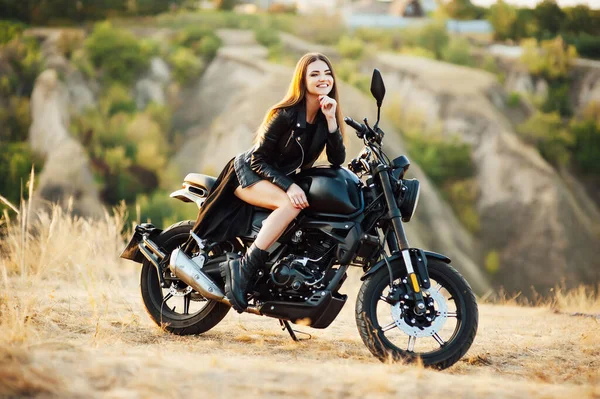 Rapariga numa mota. Ela é linda, posando em uma motocicleta ao pôr do sol — Fotografia de Stock