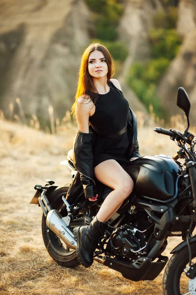 Mädchen auf einem Motorrad. Sie ist wunderschön, posiert bei Sonnenuntergang auf einem Motorrad — Stockfoto