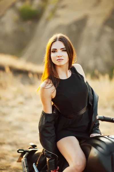 Mädchen auf einem Motorrad. Sie ist wunderschön, posiert bei Sonnenuntergang auf einem Motorrad — Stockfoto