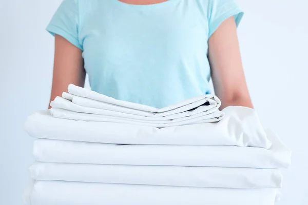 Hemmafru som innehar en stack av tvättat sängkläder. tvätta kläder och sängkläder, blekning av vita saker — Stockfoto