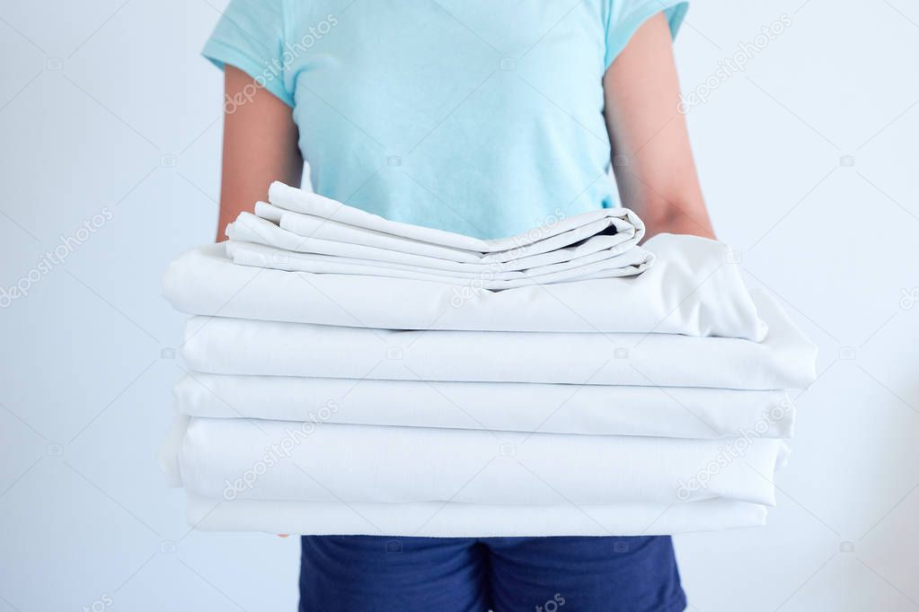 housewife holding a stack of washed bed linen. washing clothes and linen, bleaching of white things
