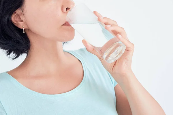 Glücklich schöne junge Frau, die Wasser trinkt. Lächelndes kaukasisches Model mit transparentem Glas in der Hand. Nahaufnahme. Fokus auf den Arm — Stockfoto