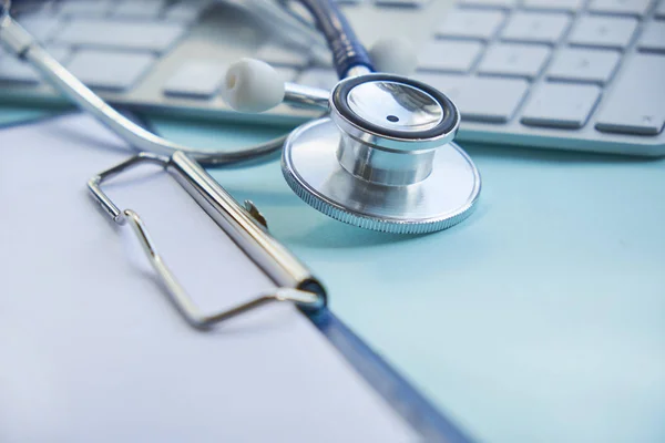 Stetoskop med Urklipp och Laptop på skrivbord, läkare som arbetar på sjukhuset skriver recept. Hälso- och sjukvård koncept, testresultat i bakgrunden, selektivt fokus — Stockfoto