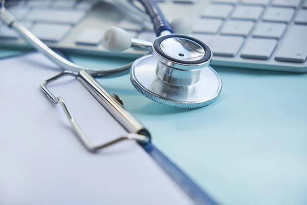 Estetoscopio con portapapeles y computadora portátil en el escritorio, Doctor trabajando en el hospital escribiendo una receta. Salud y concepto médico, resultados de las pruebas en el fondo, enfoque selectivo — Foto de Stock