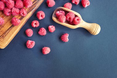 Siyah arka plan üzerine taze organik ahududu. bir tahta kaşık çilek