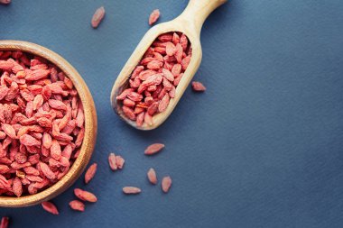 Goji kase ahşap masa üzerinde. Üstten görünüm kepçe ve kase taze Goji. Goji tablo üzerinde kalp şeklinde.