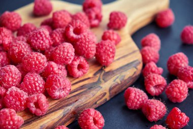 Siyah arka plan üzerine taze organik ahududu. bir ahşap tahta üzerinde çilek