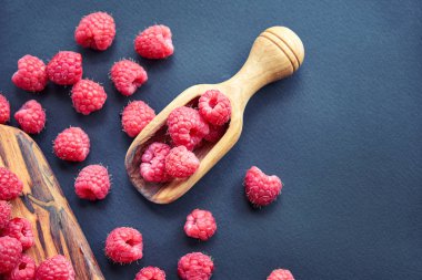 Siyah arka plan üzerine taze organik ahududu. bir tahta kaşık çilek