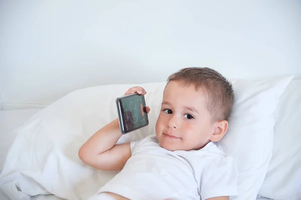 Хлопчик перед сном і дивиться мультфільми в смартфоні — стокове фото