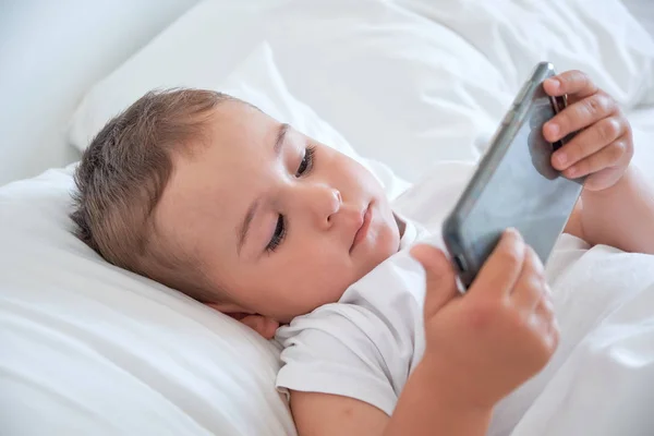 Bébé garçon avant d'aller au lit et de regarder des dessins animés dans le smartphone — Photo