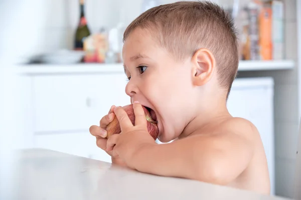 台所でりんごを食べて変な少年. — ストック写真