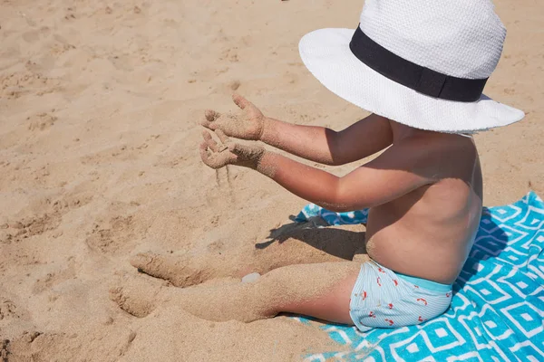 Estilo de vida das crianças ao ar livre. Menino bonito feliz no panamá brincando com areia na praia do mar. Férias de verão e conceito de viagem familiar. Pequeno bebê sentado na areia perto do mar — Fotografia de Stock