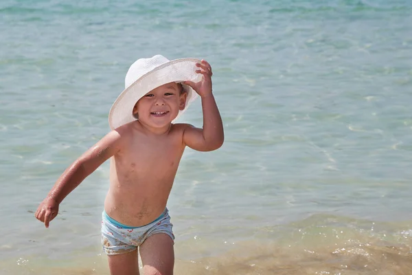 Υπαίθριο τρόπο ζωής τα παιδιά. Ευτυχισμένο το χαριτωμένο αγόρι στον Παναμά παίζοντας με άμμο στην παραλία της θάλασσας. Καλοκαιρινές διακοπές και οικογενειακά ταξίδια έννοια. Μικρό μωρό κάθεται στην άμμο κοντά στη θάλασσα — Φωτογραφία Αρχείου