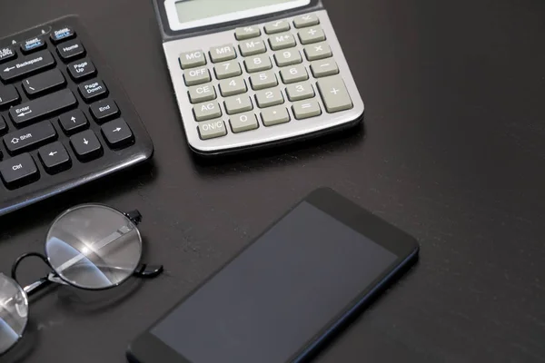 Office black Desk table with computer, calculator, smartphone, glasses, pan, supplies. Top view with copy space. Business jobs and business objects